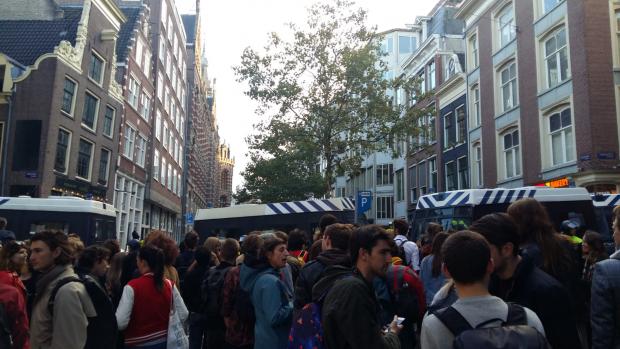 Het is erg moeilijk om te volgen wat er gebeurt. Iedereen is gedwongen op een grote afstand te staan en ME-busjes versperren het zicht.