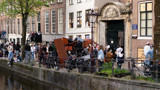 Politie grijpt vooralsnog niet inDe politie houdt de boel in de gaten, maar ziet vooralsnog geen reden tot ingrijpen. &lsquo;Het recht op demonstratie is een groot goed, maar als er eventueel strafbare feiten worden gepleegd, dan zal er eventueel worden ingegrepen&rsquo;, aldus een woordvoerder. Maar dat is volgens haar aan de driehoek: de burgemeester, OM en stadsbestuur. &nbsp;&nbsp;&lsquo;Voor nu is het wat ons betreft nog echt een demonstratie. We weten van de barricades&rsquo;, zegt de woordvoerder. &lsquo;Het protest begon op de UvA en trok toen door de stad. Wat we nu zien is dat de groepjes versplinterd zijn, er zitten wat mensen op de Dam, wat mensen rondom de Oudemanhuispoort. Van ingrijpen is er momenteel in elk geval geen sprake.&rsquo;
&nbsp;
Op zowel de Binnengasthuisstraat, de Grimburgwal als de Oudezijds Achterburgwal staat ME gestationeerd. Vooralsnog wordt niet ingegrepen en kunnen de demonstranten hun gang gaan met de bezetting en het opbouwen van de barricades. Ook wordt met graffiti een beveiligingscamera &ldquo;blind&rdquo; gespoten.