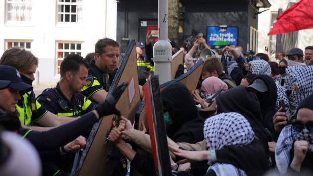 Omsingeling Spui
De ME omsingelt inmiddels het hele plein. Demonstranten en pers worden van het plein geduwd. Demonstranten maken een menselijke ketting. Agenten nemen de schilden van de demonstranten af en voeren die af. De wapenstokken worden opnieuw stevig ingezet.